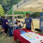 A City staffer smiling an at "Affordable Seattle" program booth at an outdoor event