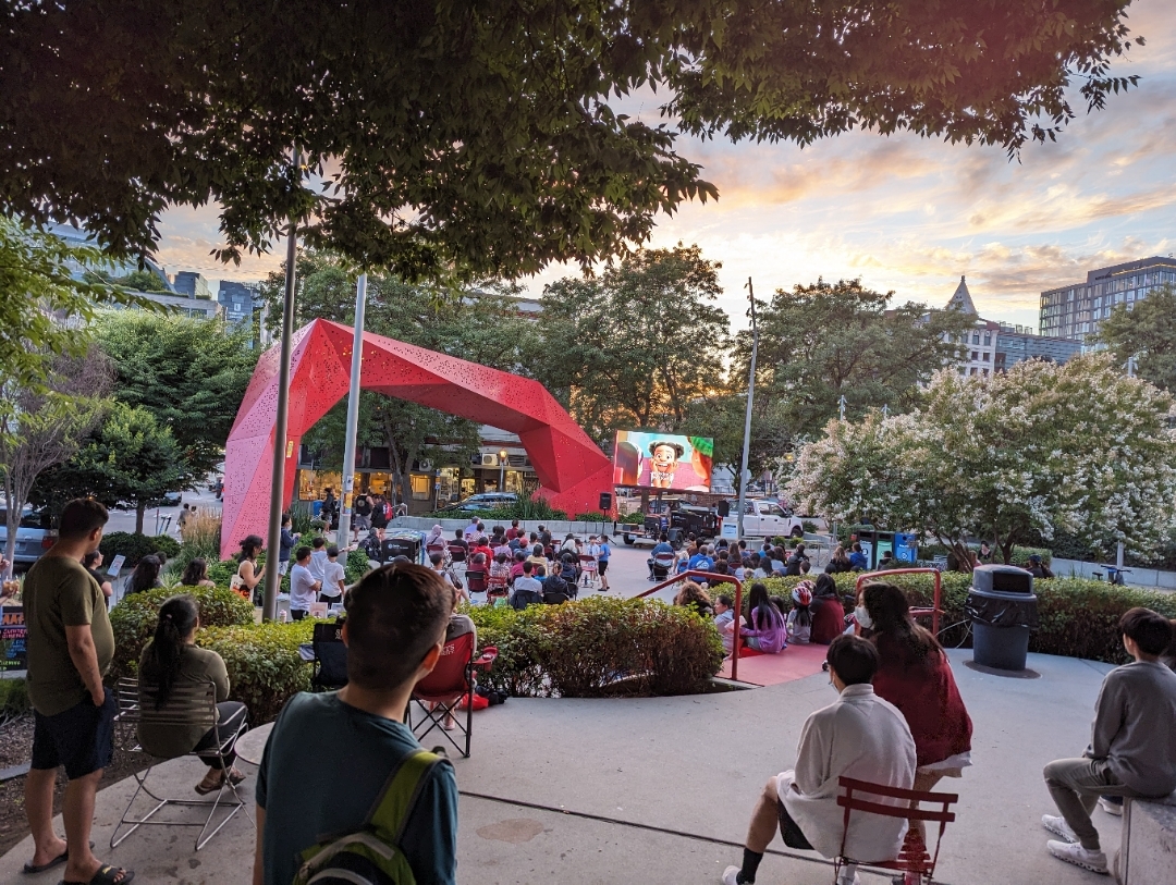 A crowd watching an animated movie at dusk at Hing Hay Park in Seattles Chinatown-International District.