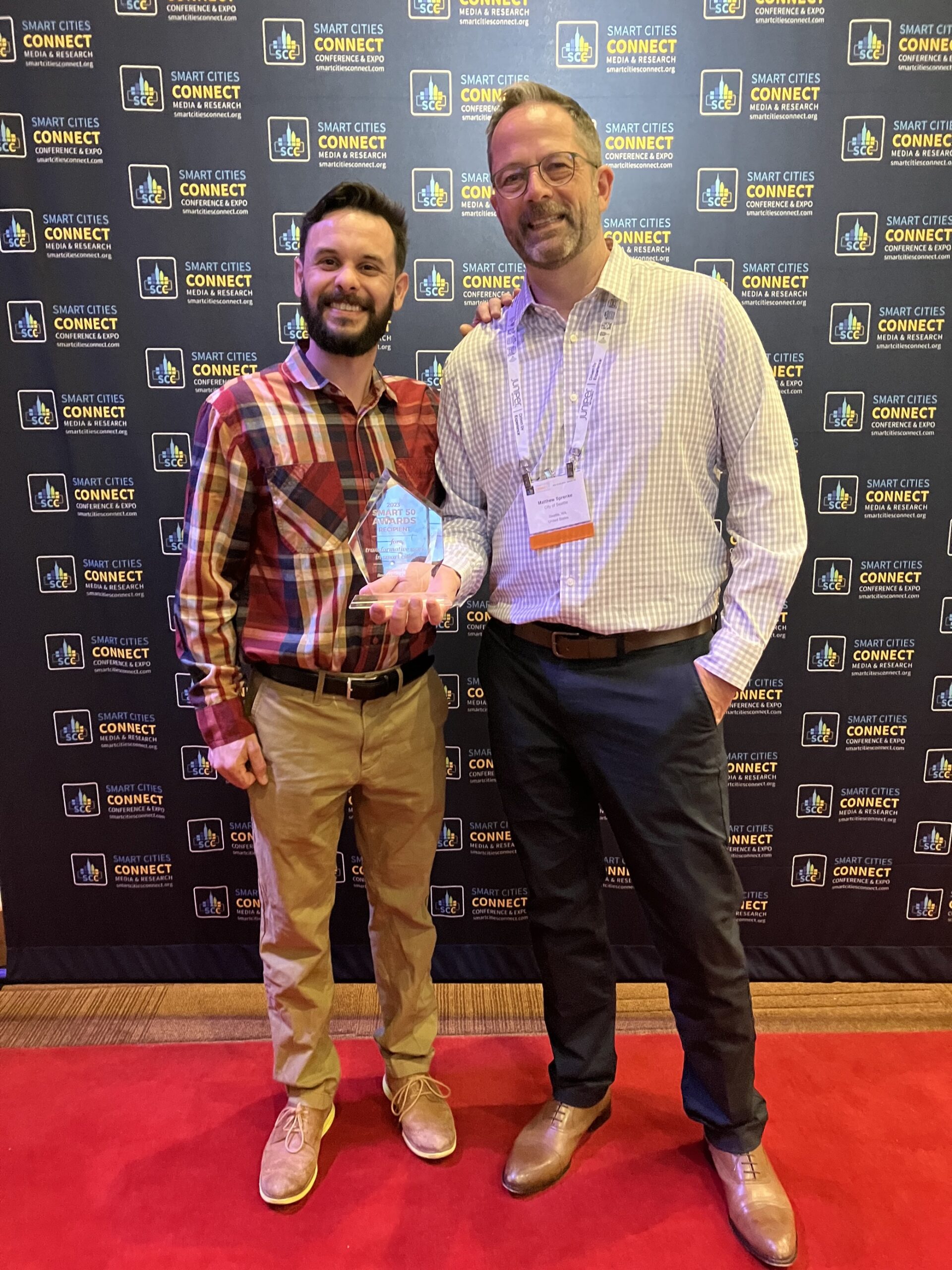 Seattle employees Miguel Jimenez and Matthew Sprenke smile from the red carpet with the Smart Cities Connect Award