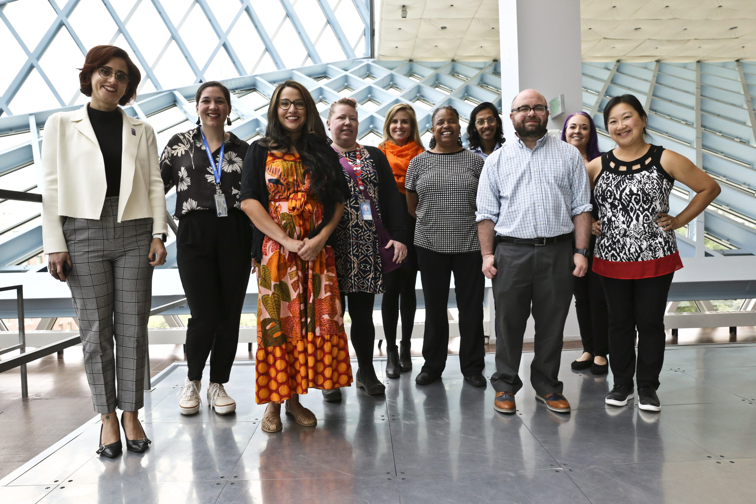 A group of ten people standing together and smiling in the downtown Seattle Public Library building