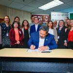 Mayor Harrell signing an Executive Order surrounded by city staff and stakeholders at a press conference