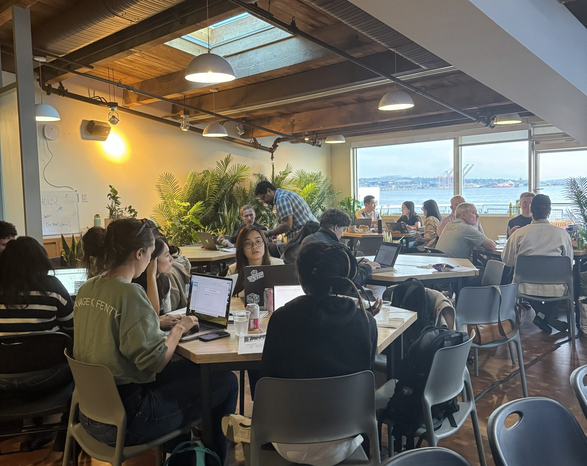 A crowd of participants working on their projects at the Community Innovation Hackathon at the AI House